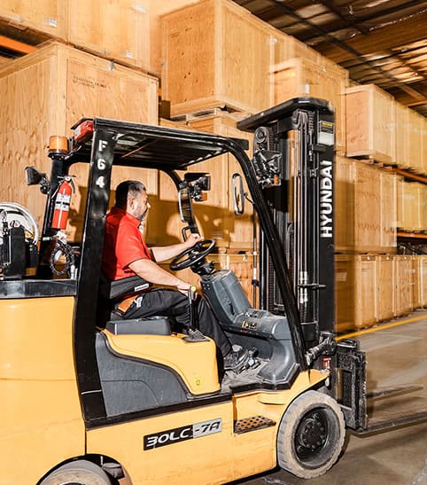 Worker Driving Forklift in Warehouse